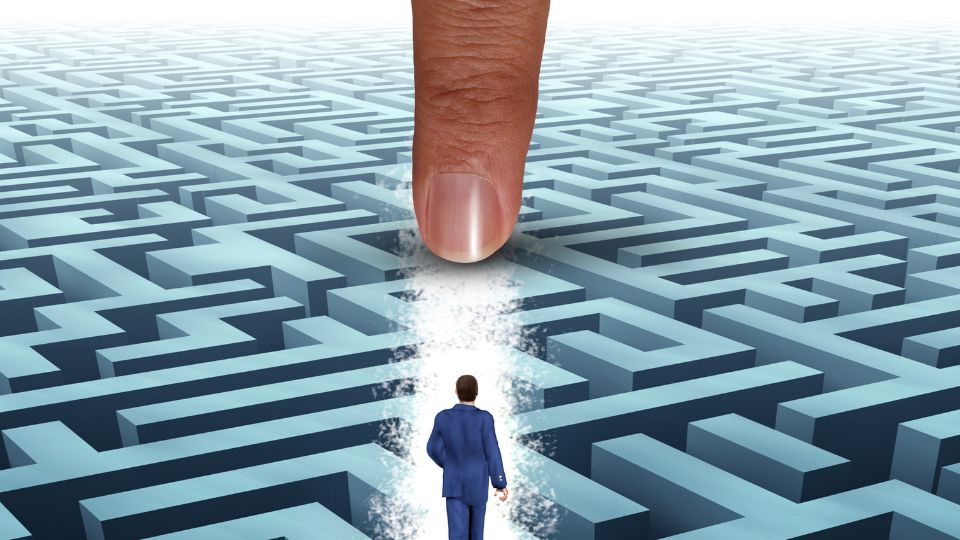 Egy üzletember egy labirintus előtt áll, miközben egy hatalmas ujj mutatja az utat.