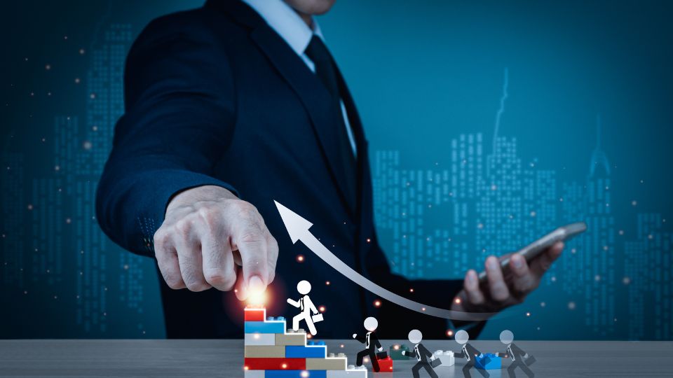 Egy üzletember mutat a növekvő grafikonra, miközben a telefonját tartja.