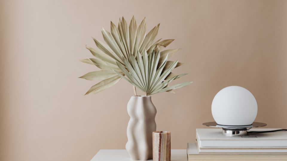 Modern dekorációs elemek, mint egy vázában lévő növény és egy lámpa.