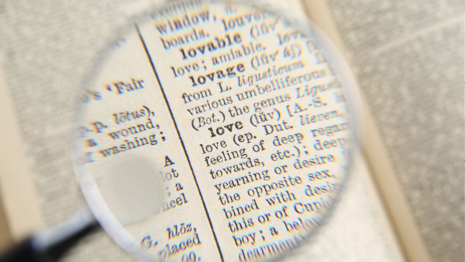 Egy lexikon oldalán a 'love' szó definíciója látható nagyítóval kiemelve.